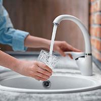 Woman pouring a drink from a tap and not wasting water