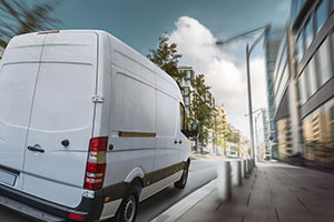 White van driving through a city